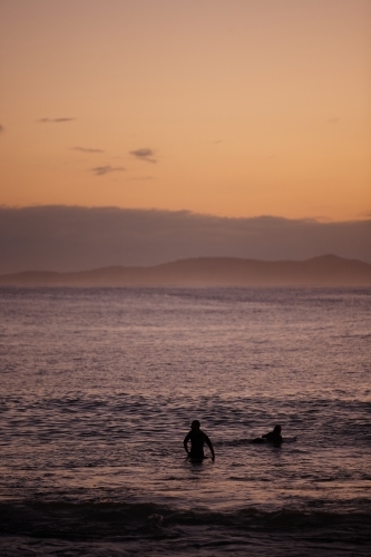 Surfers in ocean on sunrise - Australian Stock Image