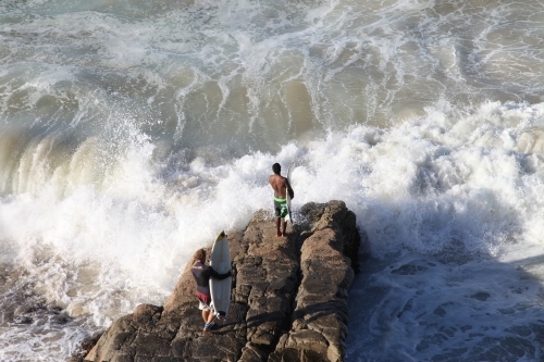 Surfers jumping off rocks - Australian Stock Image