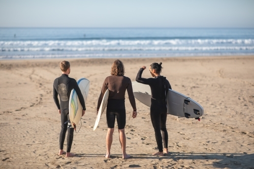 Surfers on beach looking at waves - Australian Stock Image