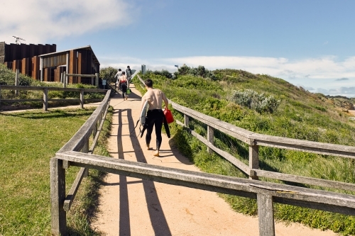 Surfers walking up a path from the beach - Australian Stock Image