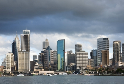 Sydney CBD from Sydney Harbour with tall buildings and dark clouds - Australian Stock Image