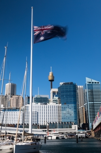 Sydney skyline from Darling harbour with Australian Flag flown half mast - Australian Stock Image