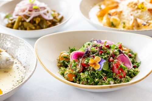 Tabouli quinoa salad topped with edible flowers and red radish. - Australian Stock Image