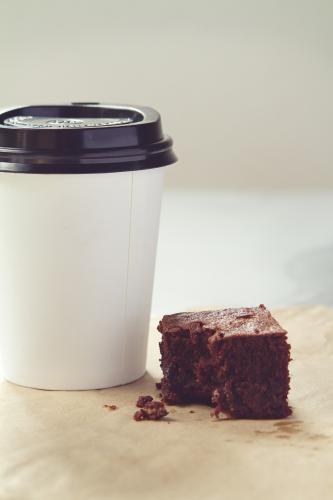 Take away coffee cup and crumbly chocolate brownie in muted tones