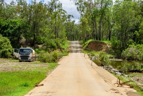 Tanker truck pumping fresh water from a creek next to a concrete flood way - Australian Stock Image