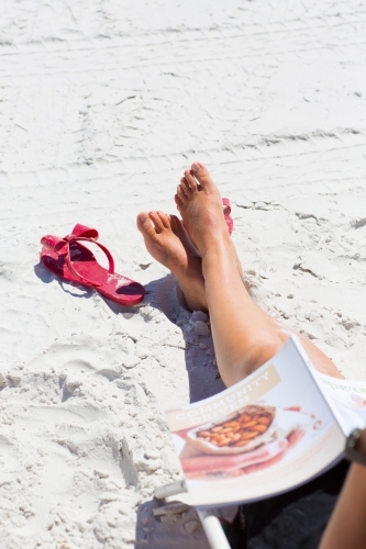 Tanned legs relaxing on a white sandy beach