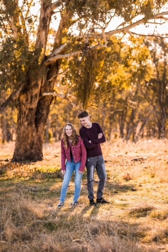 Teen girl laughing at teen boy outside in paddock on farm - Australian Stock Image