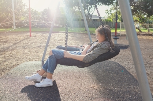 Teen girl on big swing with friend - Australian Stock Image