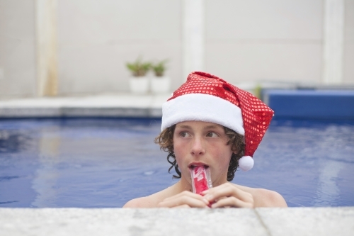 Teenage boy in Santa hat celebrating christmas in a pool - Australian Stock Image