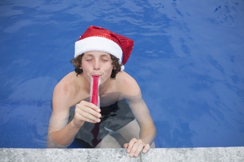 Teenage boy in Santa hat celebrating christmas in a pool - Australian Stock Image