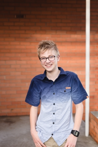 Teenage boy standing in front of red brick wall - Australian Stock Image