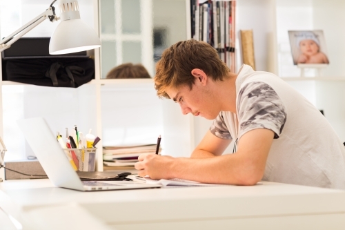 Teenage boy writing at a desk