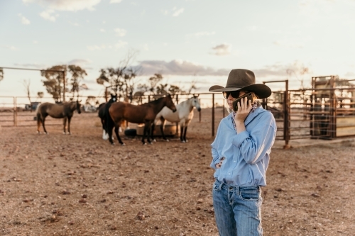 Teenage Girl Speaking on Phone in Horse Yards - Australian Stock Image