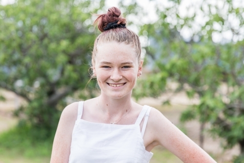 Teenage girl standing in yard at home smiling happy - Australian Stock Image