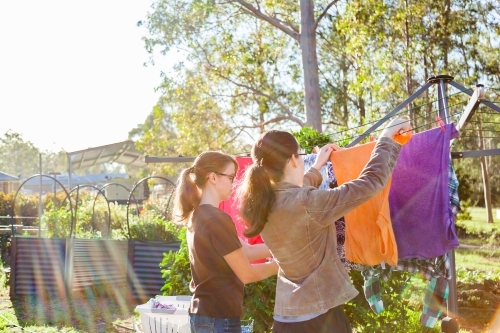 Teenage kids hanging washing up on the clothesline in the backyard - Australian Stock Image