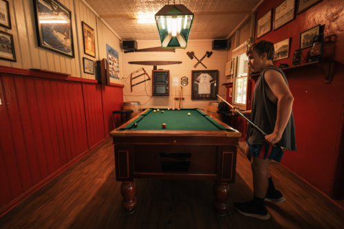 Teenage male playing 8 ball pool on billiard table in Australian pub - Australian Stock Image