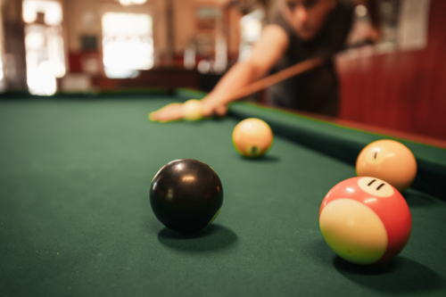 Teenage male playing 8 ball pool on billiard table in Australian pub - Australian Stock Image