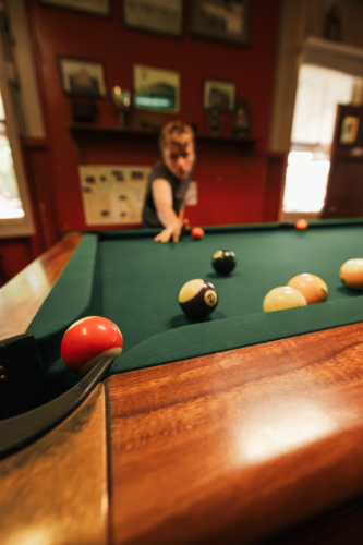 Teenage male playing 8 ball pool on billiard table in Australian pub - Australian Stock Image