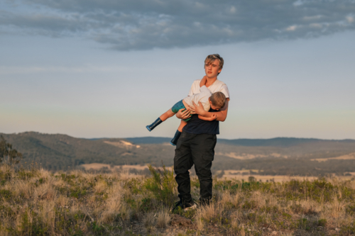 Teenager carrying little boy on hilltop - Australian Stock Image