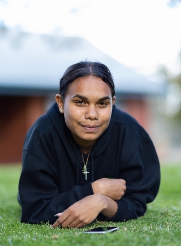 teenager laying down on lawn looking at camera - Australian Stock Image