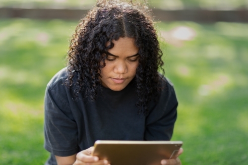 teenager outside on grass holding digital tablet - Australian Stock Image