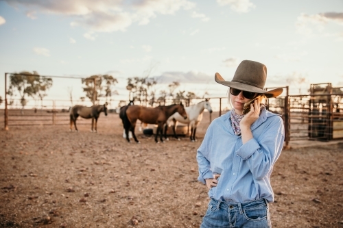 Teenager talking on a mobile phone while standing in the horse yard - Australian Stock Image