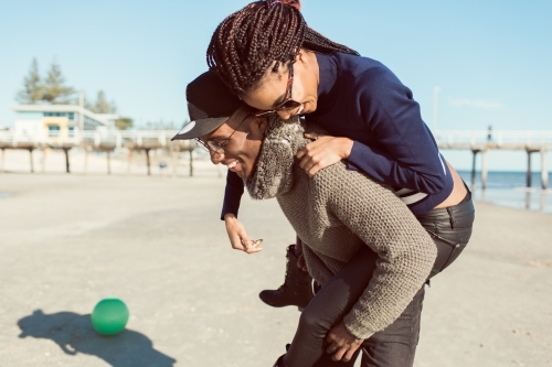 Teenagers playing piggy back on the beach - Australian Stock Image