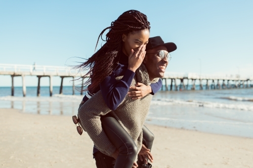 Teenagers playing piggy back on the beach - Australian Stock Image