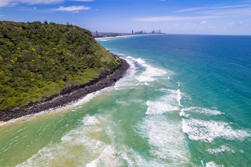 The city coming into view as the drone flies around the headland in the Gold Coast - Australian Stock Image