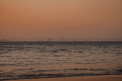 The Glasshouse Mountains visible from Moreton Island at sunset - Australian Stock Image