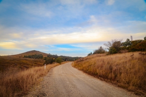 The road out of Sofala NSW Australia. Winding dirt lane through rolling hills - Australian Stock Image