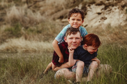 Three brothers sitting together on a rock in the Australian bush - Australian Stock Image