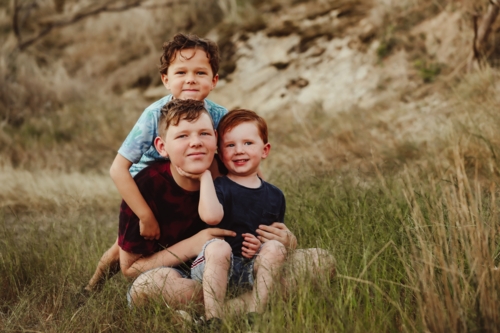 Three brothers sitting together on a rock in the Australian bush - Australian Stock Image