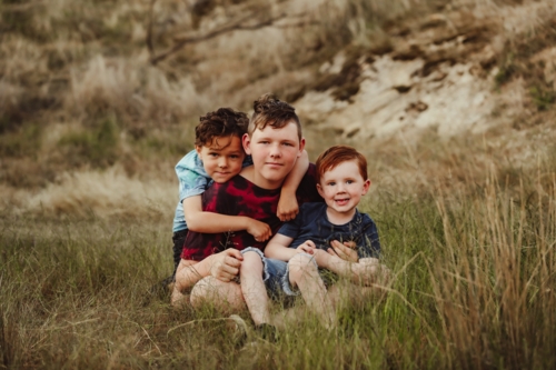 Three brothers sitting together on a rock in the Australian bush - Australian Stock Image