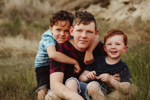 Three brothers sitting together on a rock in the Australian bush - Australian Stock Image