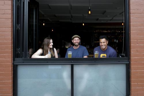 Three friends at a window having a drink at a local craft beer bar