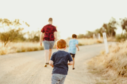 Three kids walking along gravel road in the countryside - Australian Stock Image