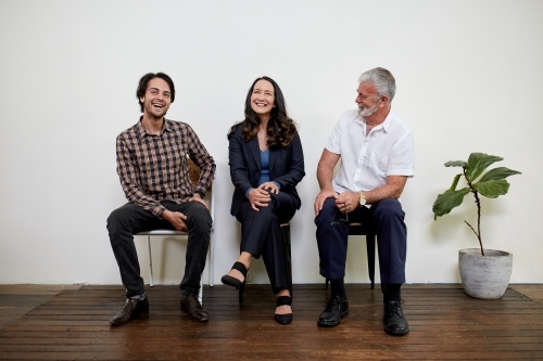 Three professional business people sitting in a row in a studio