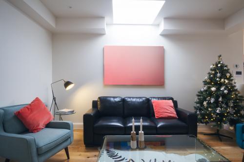 Three seater sofa in living room with christmas tree and blank artwork
