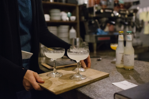 Three stemmed glasses of cocktail served on a wooden board - Australian Stock Image