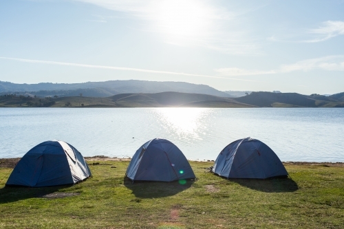 Three tents pitched for camping by the water on edge of Lake St Clair in Hunter Valley - Australian Stock Image