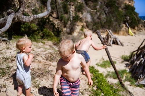 Three young boys playing together on a sand dune on a warm, sunny day. - Australian Stock Image