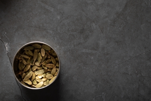 Tin of cardamon pods on dark marble background - Australian Stock Image