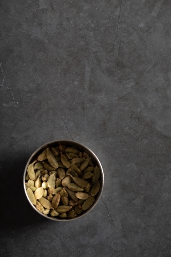 Tin of cardamon pods on dark marble background - Australian Stock Image