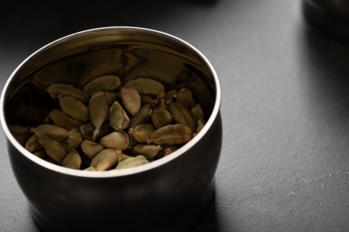 Tin of cardamon pods on dark marble background - Australian Stock Image