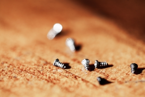 Tiny screws on wooden tabletop - Australian Stock Image