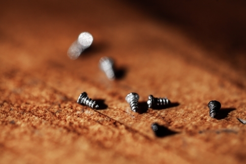 Tiny screws on wooden tabletop - Australian Stock Image