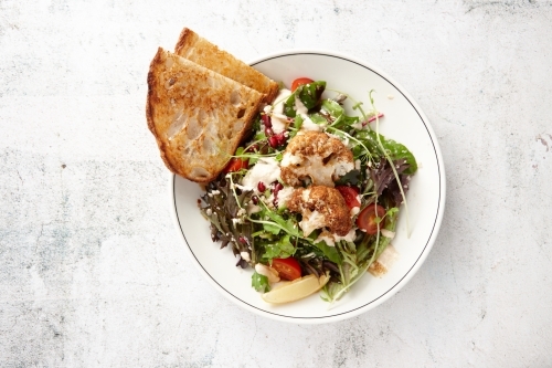 Toast with vegetarian cauliflower salad in bowl - Australian Stock Image