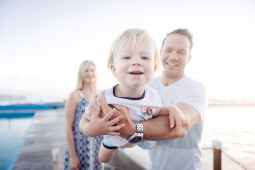 Toddler boy in fathers arms at the beach - Australian Stock Image