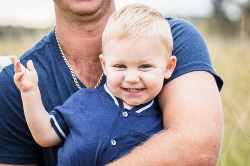 Toddler boy smiling in father's arms - Australian Stock Image